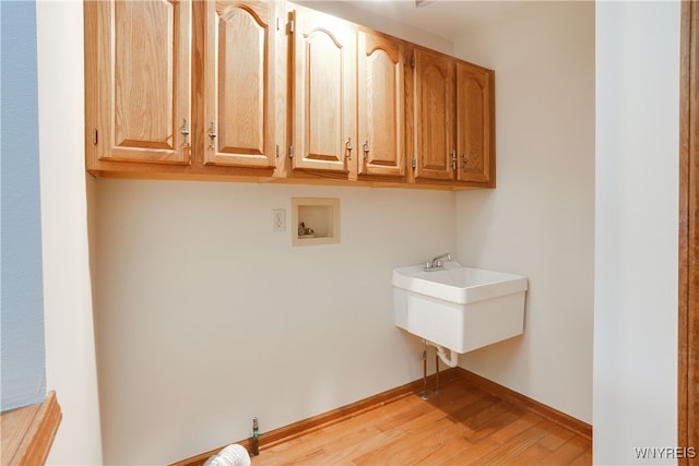 laundry room featuring hookup for a washing machine, light hardwood / wood-style flooring, cabinets, and sink