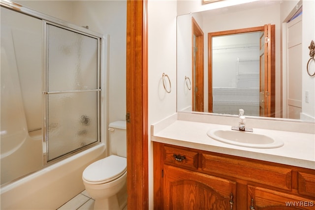 full bathroom with tile patterned floors, vanity, toilet, and bath / shower combo with glass door