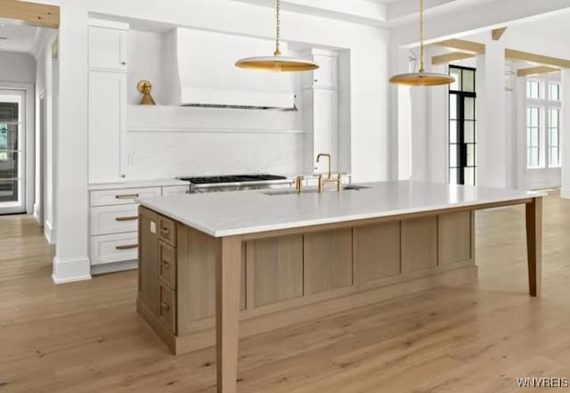 kitchen with decorative light fixtures, a healthy amount of sunlight, a spacious island, and white cabinetry