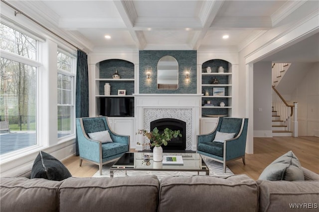 living room featuring beamed ceiling, light hardwood / wood-style flooring, coffered ceiling, and a tiled fireplace