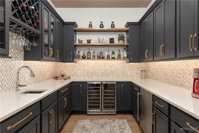 bar featuring decorative backsplash, sink, beverage cooler, and light hardwood / wood-style flooring