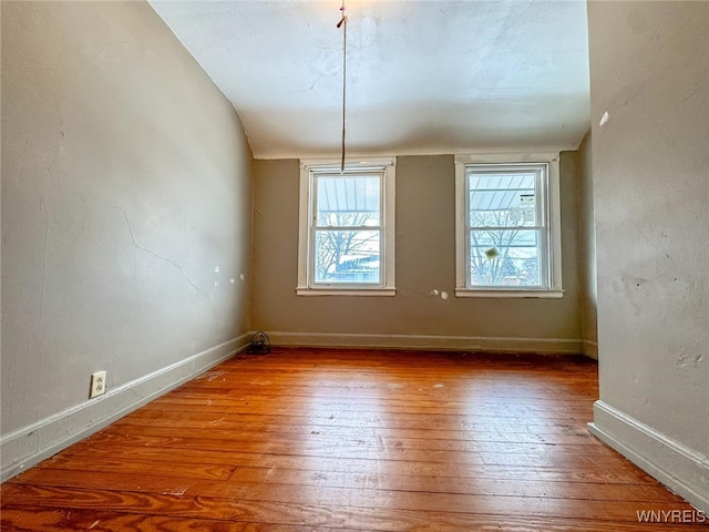 empty room featuring lofted ceiling and hardwood / wood-style flooring