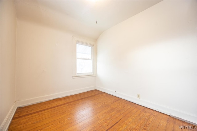 spare room featuring hardwood / wood-style floors and vaulted ceiling