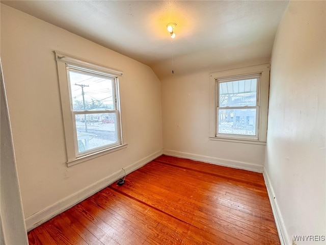 spare room featuring wood-type flooring and lofted ceiling