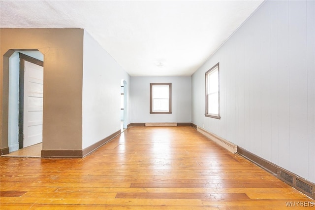 empty room with a baseboard radiator and light hardwood / wood-style flooring