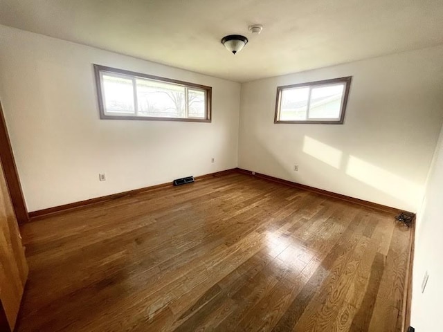 empty room with hardwood / wood-style floors and a healthy amount of sunlight