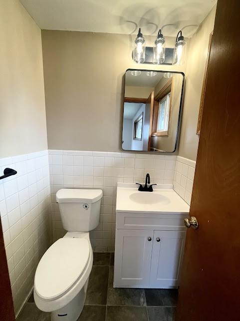 bathroom featuring tile patterned flooring, vanity, tile walls, and toilet