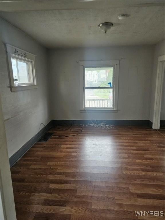 spare room with dark wood-style flooring, baseboards, and a wealth of natural light