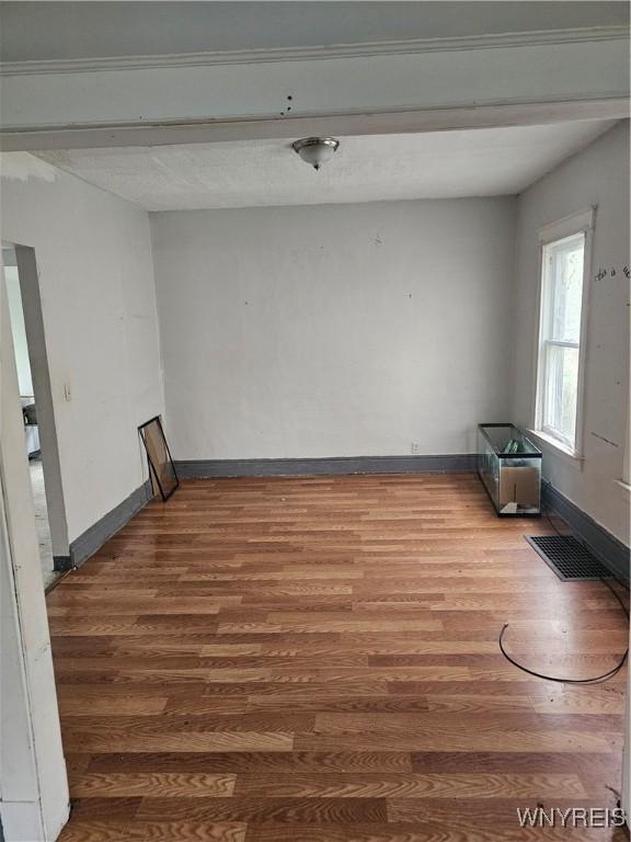 spare room featuring baseboards, wood finished floors, and visible vents