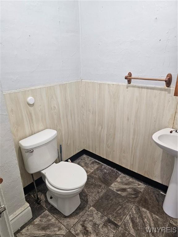 half bathroom featuring toilet and a wainscoted wall