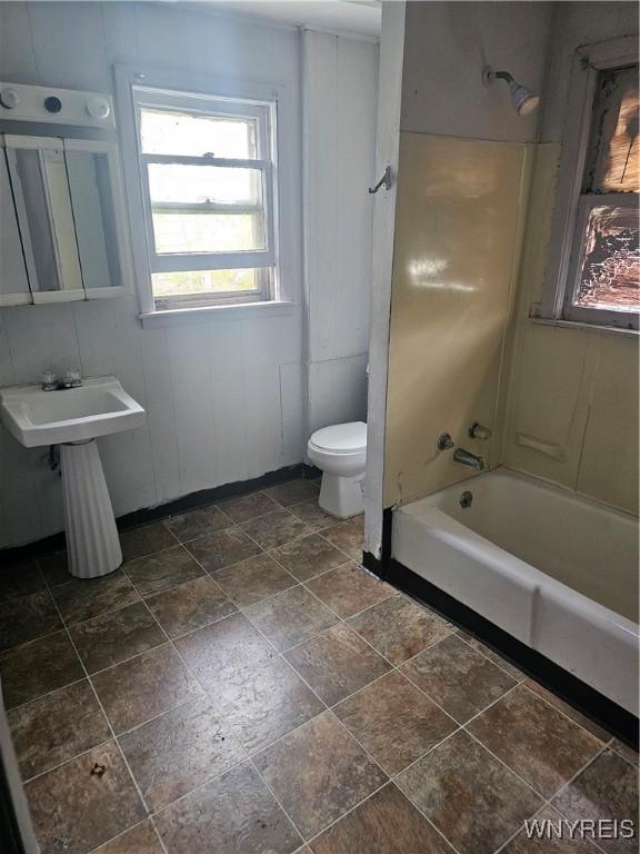 bathroom featuring a sink, bathtub / shower combination, stone finish floor, and toilet
