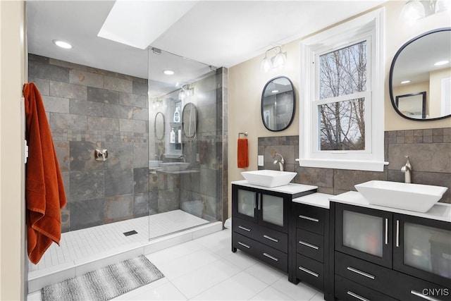 bathroom with a tile shower, vanity, tile patterned floors, and tile walls