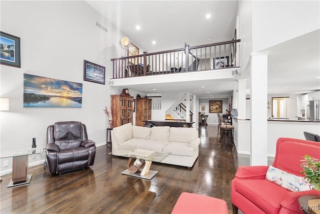 living room with ornate columns, a towering ceiling, and hardwood / wood-style flooring