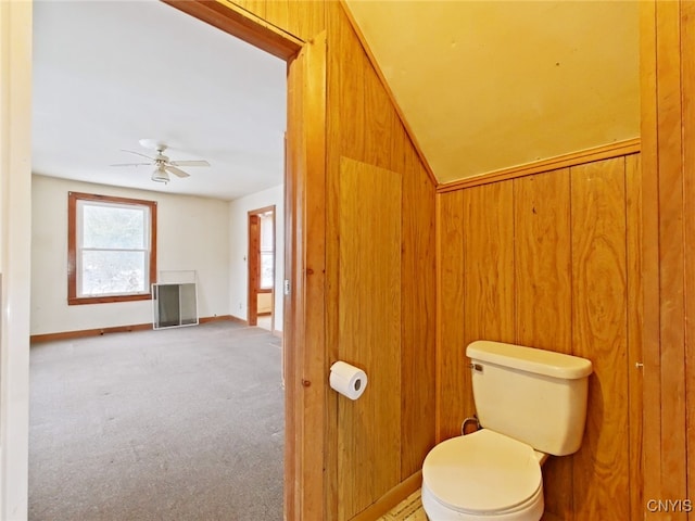 bathroom with wood walls, ceiling fan, and toilet