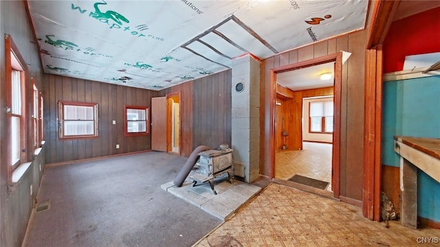 interior space with a wood stove, a wealth of natural light, and wood walls