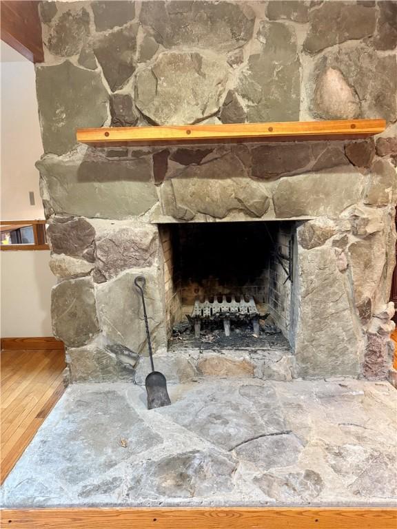 details with hardwood / wood-style flooring and a stone fireplace