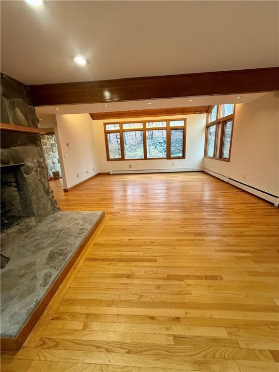 unfurnished living room with plenty of natural light, a fireplace, and light hardwood / wood-style flooring