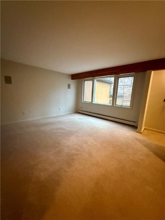 carpeted empty room with a baseboard heating unit