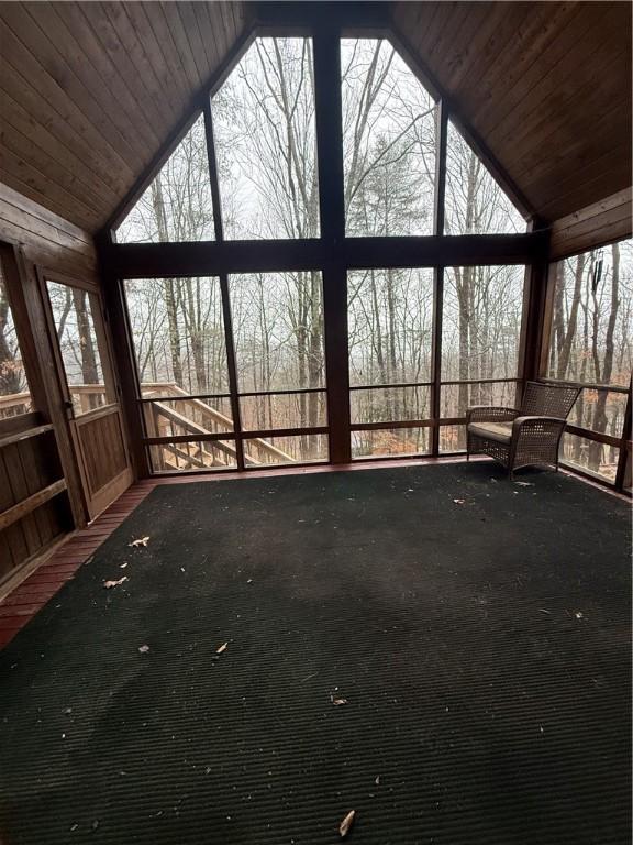 unfurnished sunroom featuring a wealth of natural light, wooden ceiling, and lofted ceiling