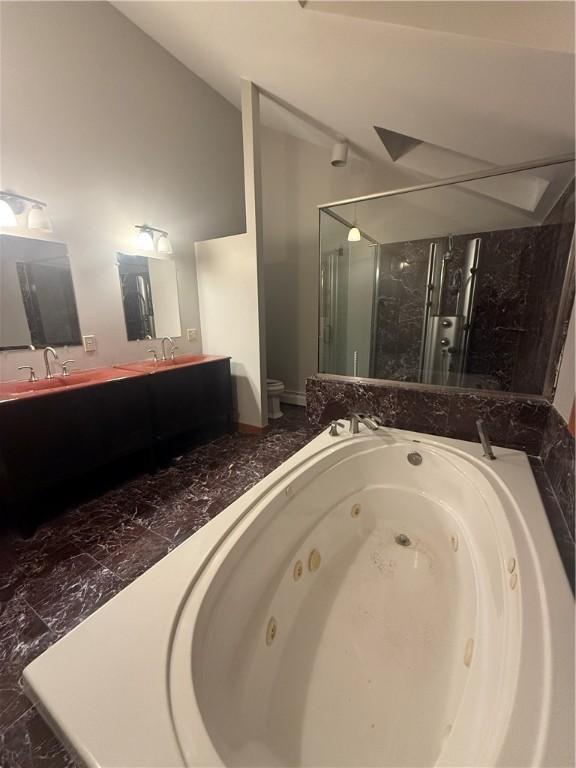 bathroom featuring vanity, independent shower and bath, and vaulted ceiling