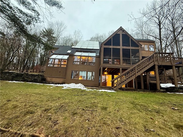 back of house with a sunroom, a yard, and solar panels