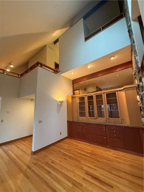 unfurnished living room featuring a high ceiling and light wood-type flooring