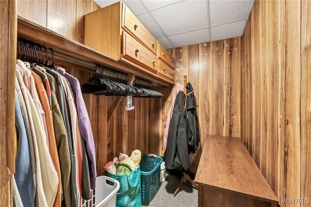 mudroom with wood walls, a drop ceiling, and light colored carpet