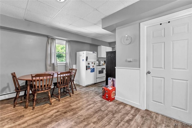 dining space with light hardwood / wood-style floors and a drop ceiling