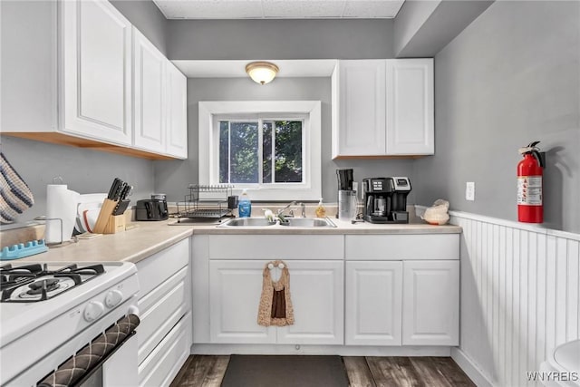 kitchen with white cabinets, dark hardwood / wood-style floors, sink, and white range with gas cooktop