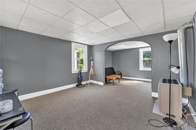 living area with a paneled ceiling, carpet floors, and heating unit