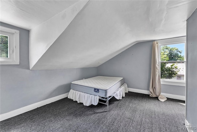 bedroom featuring dark carpet, multiple windows, and vaulted ceiling