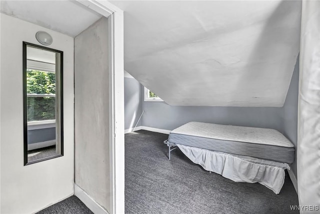 bedroom with dark colored carpet and lofted ceiling