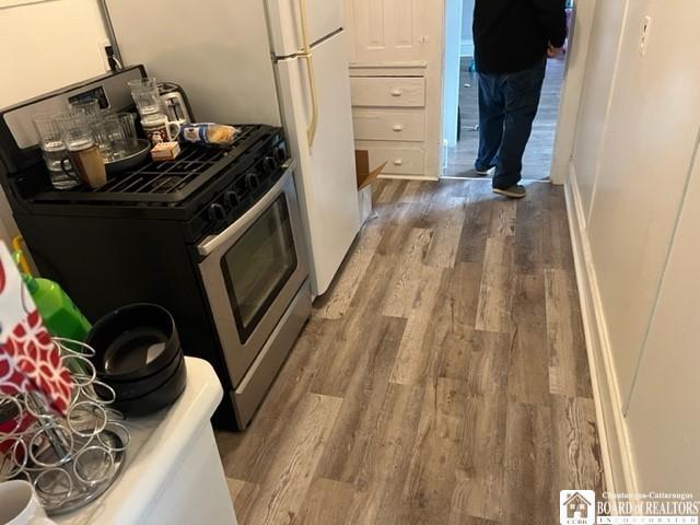 kitchen with stainless steel range with gas cooktop, light hardwood / wood-style flooring, and white cabinets