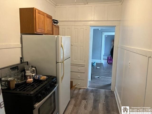 kitchen with white fridge, dark wood-type flooring, and stainless steel gas range