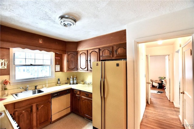 kitchen featuring a textured ceiling, white appliances, sink, and light hardwood / wood-style flooring