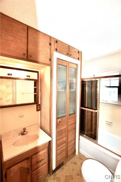 full bathroom featuring vanity, enclosed tub / shower combo, and toilet