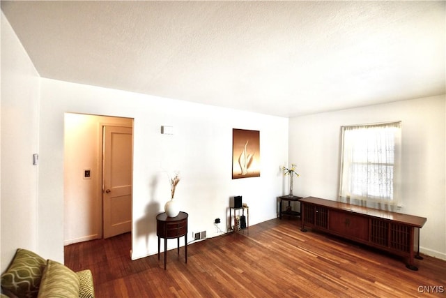 living room featuring dark wood-type flooring and a textured ceiling