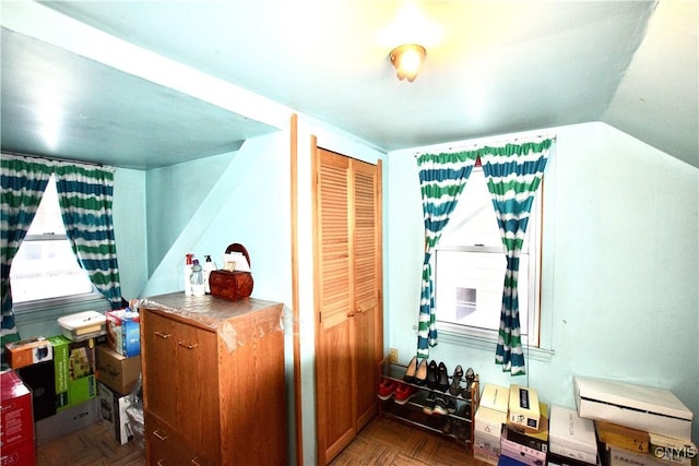 interior space featuring parquet floors, a closet, and lofted ceiling