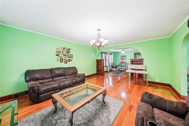 living room featuring hardwood / wood-style floors, ornamental molding, and a notable chandelier