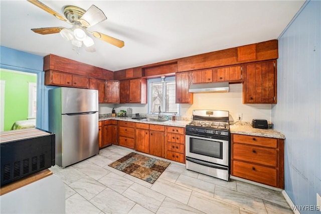 kitchen featuring ceiling fan, wood walls, sink, and appliances with stainless steel finishes