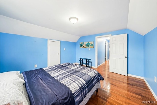 bedroom with wood-type flooring and vaulted ceiling