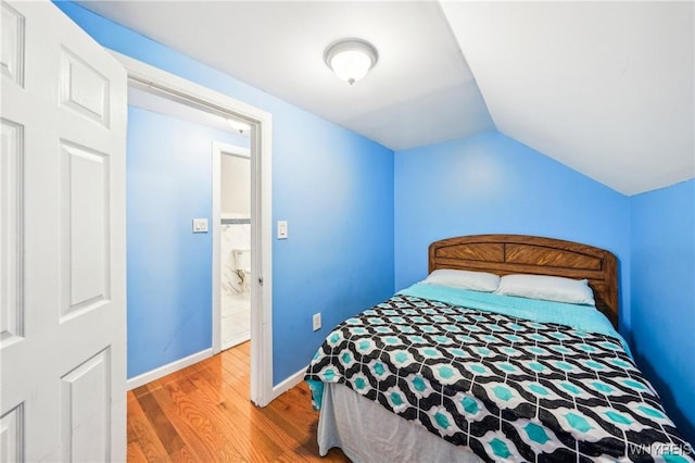 bedroom with lofted ceiling and wood-type flooring