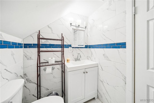 bathroom with vanity, toilet, and tile walls