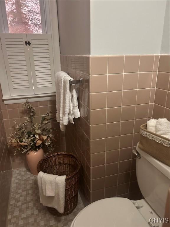 bathroom with tile walls and toilet