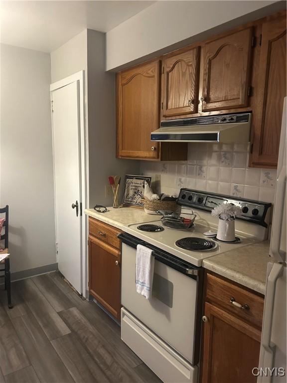 kitchen featuring dark hardwood / wood-style floors, white appliances, extractor fan, and tasteful backsplash