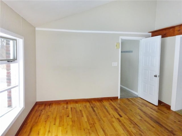 spare room featuring light hardwood / wood-style flooring and vaulted ceiling