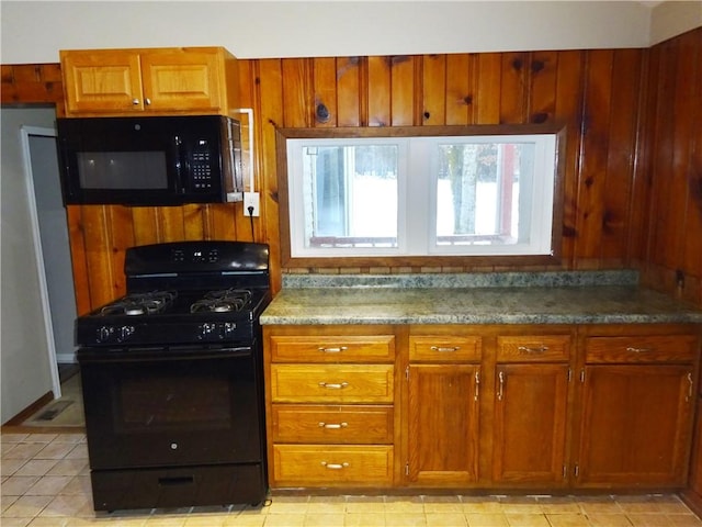 kitchen featuring light stone counters, light tile patterned floors, and black appliances