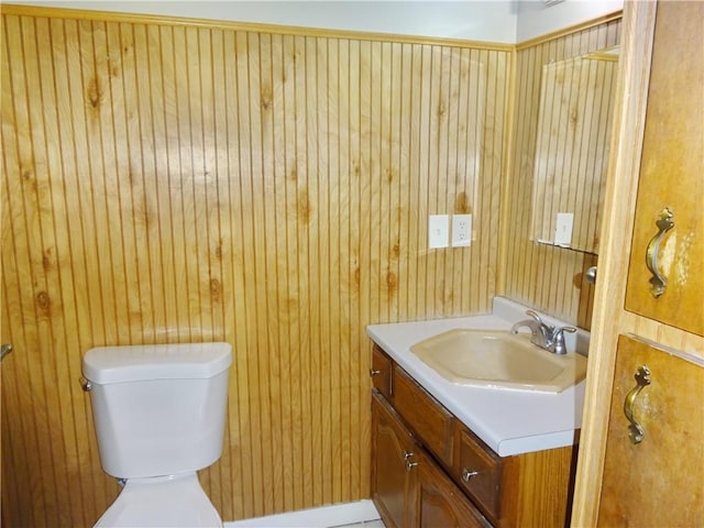 bathroom with vanity, toilet, and wooden walls