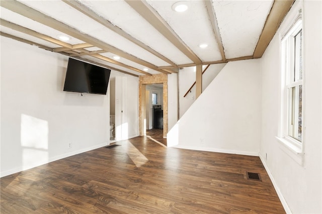 unfurnished living room featuring dark wood-type flooring and beam ceiling