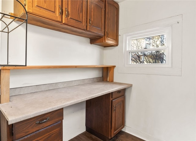 unfurnished office featuring dark hardwood / wood-style flooring and built in desk